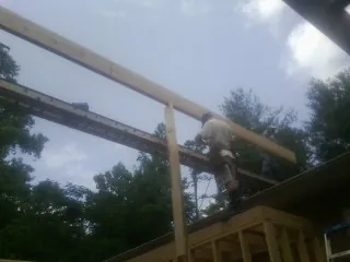 Carpenter setting a ridge beam over a new addition frame — Ice Dam Removal by Roofing Brothers in Moreland