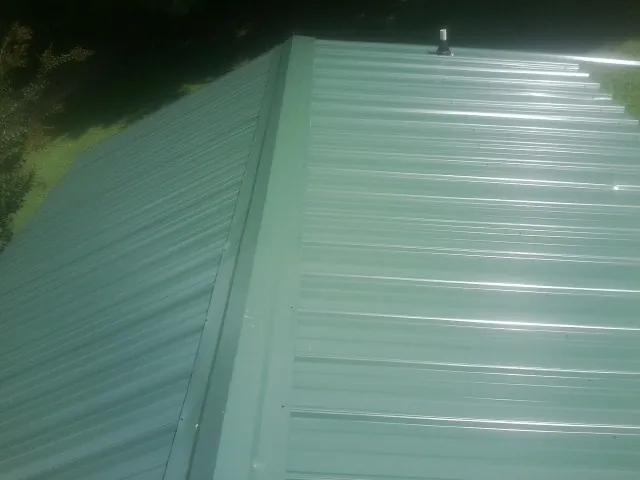 New green metal panels meeting at the ridge of a roof — Flat Roof Repair work by our crew in Moreland