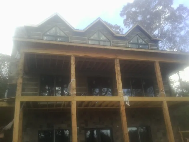 Dormers and porch framing on a large log home under construction — Roof Coating work by our crew in Moreland