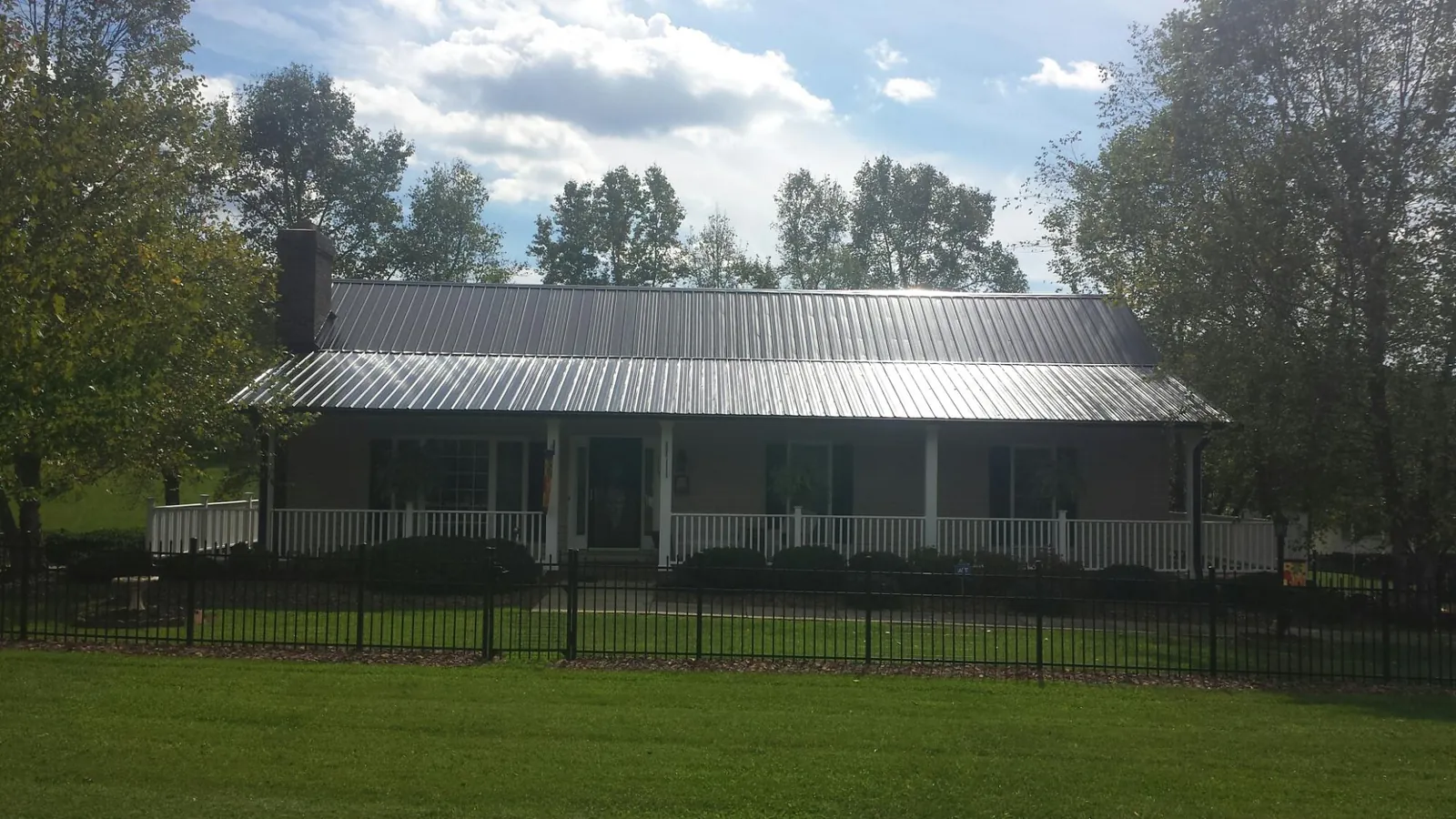 Gray metal roof on a brick ranch with a full width front porch — Gutter Guard Installation work by our crew in Moreland