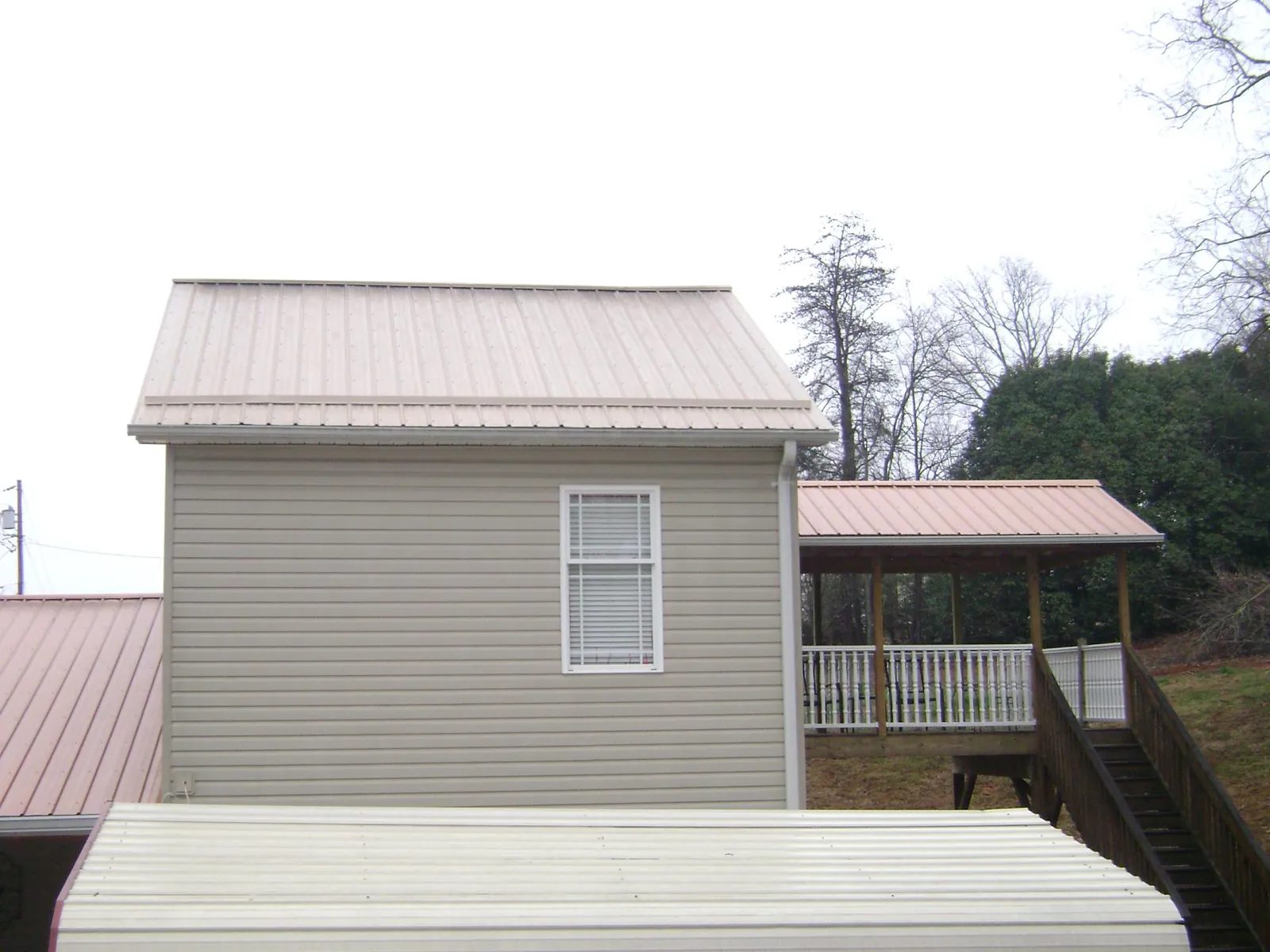 Tan metal roofs on a two story addition and attached porch, from a Roof Replacement job in Moreland